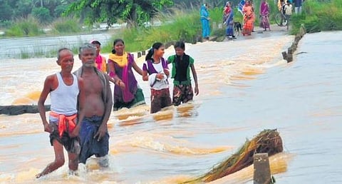 Villagers navigating the strong currents on a flooded road in Kendrapara | Express