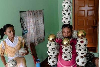 Twelve year-old Han Myint Mo (L) watching her grandfather Ohn Myint (C) balance balls during a juggling training session at a residence in Yangon. (Photo | AFP)