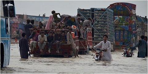Displaced Pakistani families from flood hit areas board vehicles while they move to safe place, in Nasirabad. (Photo | PTI)