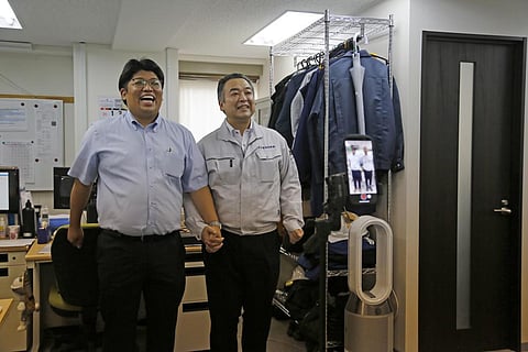 Daikyo Security Chief Executive Daisuke Sakurai, left, and General Manager Tomohiko Kojima take a Tik Tok video together as seen on the screen in the device. (Photo | AP)