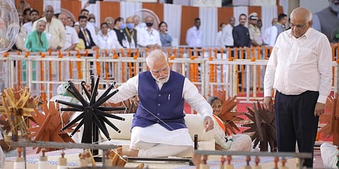 Prime Minister Narendra Modi tries his hand on a spinning wheel during 'Khadi Utsav' in Ahmedabad. (Photo | PTI)