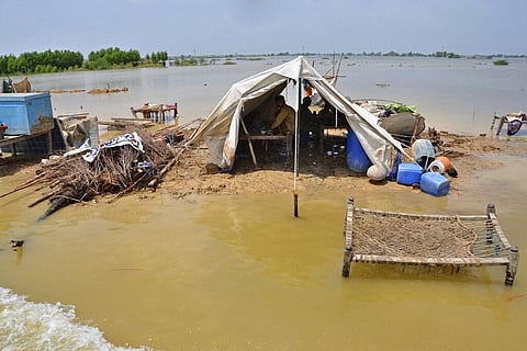 A family sits under a tent sep up next to their demolished house, surrounded by floodwaters, in Sohbatpur, a district of Pakistan's southwestern Baluchistan province. (Photo | AP)
