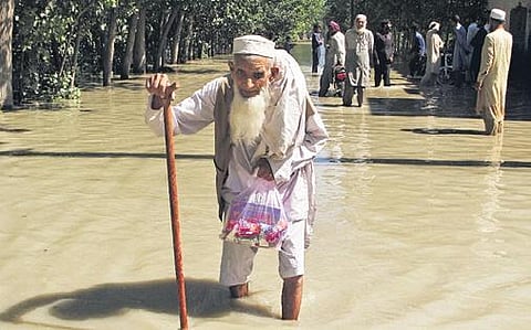 An old man wades through a flooded street on the outskirts of Peshawar | ap