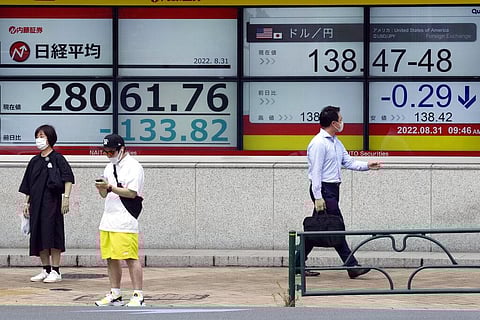 People wearing protective masks stand in front of an electronic stock board showing Japan's Nikkei 225 index at a securities firm Wednesday, Aug. 31, 2022, in Tokyo. (Photo | AP)