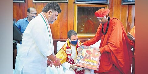 Murugha Mutt pontiff Shivamurthy Murugha Sharanaru presents Rahul Gandhi with the coffee table book ‘The Social Reformer’, brought out by The New Indian Express, at the mutt. (Photo| EPS