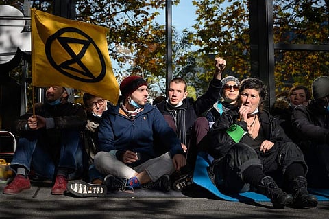 Activists seat blocking an entrance at Geneva airport's private jet terminal, during a protest by the climate change action group Extinction Rebellion (XR). (Photo | AFP)
