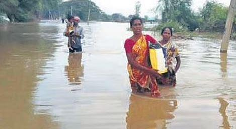 A family wades through floodwater to reach a hospital in the absence of boat to shift people from submerged Kunavaram village in ASR district | Express