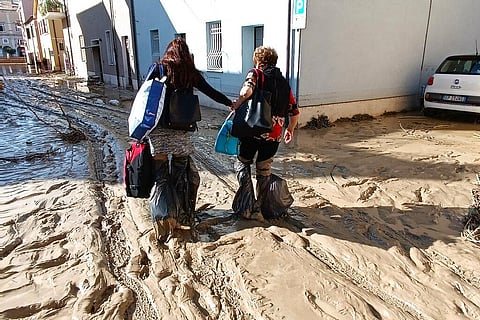 People walk on mud and debris in Senigallia, Italy. (Photo | AP)