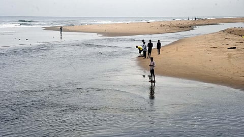 People dipping their feet in the waters at a beach in Tamil Nadu.