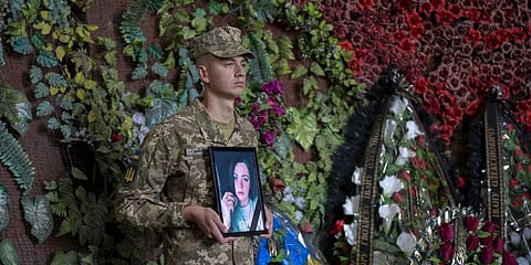 A Ukrainian soldier holds a photo of Olga Simonova, 34, a Russian woman who was killed in the Donetsk region while fighting on Ukraine's side. (Photo | AP)