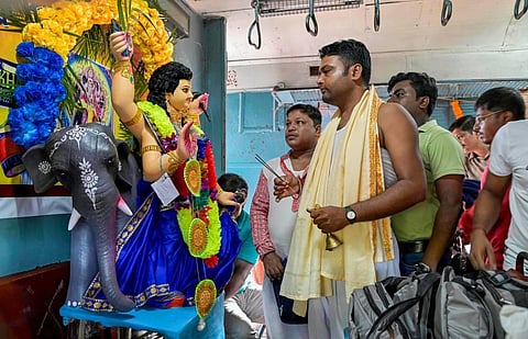 Commuters offer prayers to Lord Vishwakarma inside a Sealdah bound train coach on the occasion of Vishwakarma Puja, at Santipur station in Nadia district. (Photo | PTI)