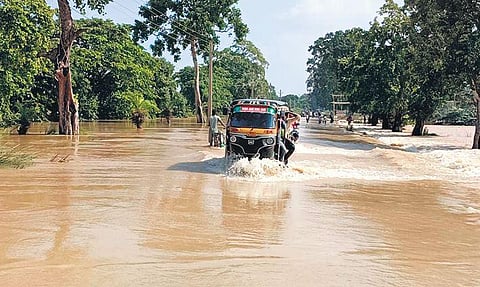 Commuters crossing the overflowing Baliapal-Basta road in Balasore district on Sunday. (Photo | Express)