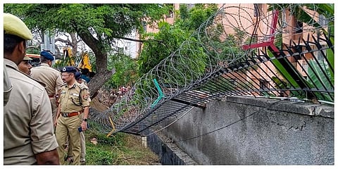 Police inspect the site after a portion of a boundary wall of a housing society collapsed, at Jal Vayu Vihar in Noida. (Photo |PTI)