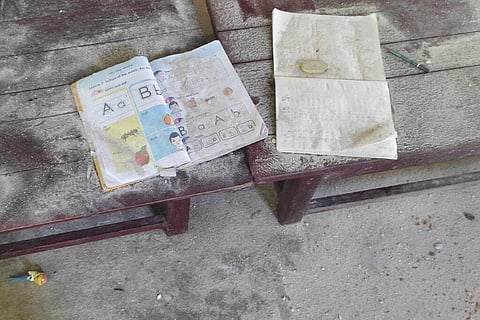 An alphabet book and a notebook lie on top of an elevated wooden floorboard of a middle school, the day after an air strike hit the school in Tabayin township, Sagaing. (Photo | AP)