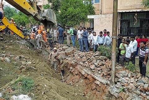 Rescue operation underway after a portion of a boundary wall of a housing society collapsed, at Jal Vayu Vihar in Noida on Tuesday. (Photo | PTI)