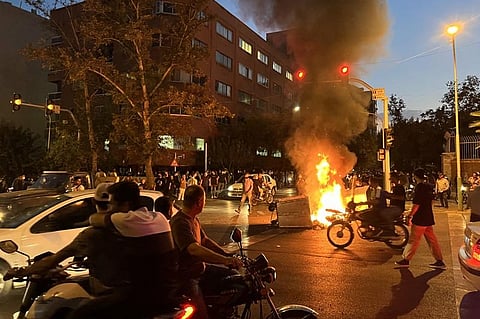Demonstrators gather around a burning barricade during a protest for Mahsa Amini, a woman who died after being arrested by 'morality police', in Tehran. (Photo | AFP)