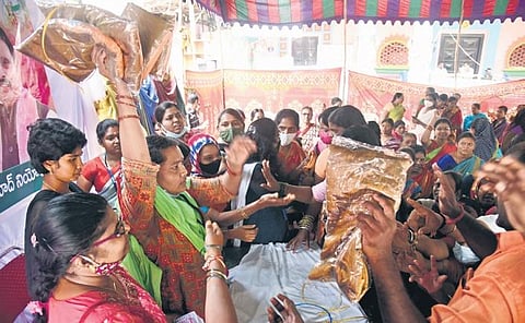 Women grab Bathukamma sarees at a distribution centre in Hyderabad on Wednesday