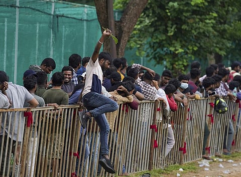 A man jumps a railing to take a break as people line up to buy tickets for the third Twenty20 cricket match between India and Australia in Hyderabad, Thursday, Sept. 22, 2022. (Photo | AP)