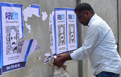 Police personnel remove posters accusing Chief Minister Basavaraj Bommai’s government of graft, pasted by unknown people on a compound wall, in Bengaluru on Wednesday. (Photo | Shashidhar Byrappa)