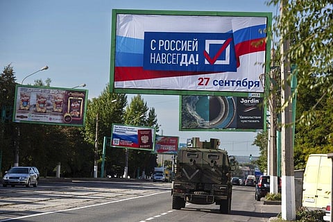 A military vehicle drives along a street with a billboard that reads: 'With Russia forever, September 27' (File photo | AP)