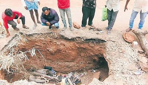 Residents stand near the pit into which the biker fell on Wednesday.  The bike is yet to be lifted out of the pit | D Hemanth