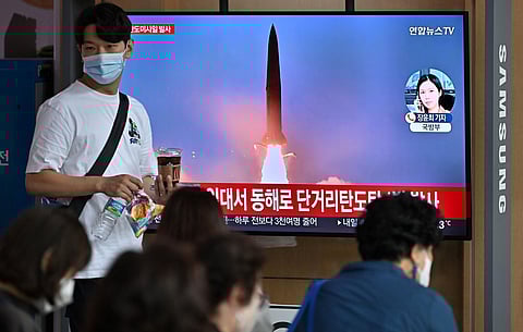 People watch a television screen showing a news broadcast with file footage of a North Korean missile test, at a railway station in Seoul on September 25, 2022.(Photo | AFP)