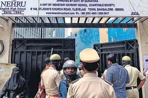 Police personnel keep vigil, as parents and students of Nehru School hold a protest in front of the closed institution in Bengaluru on Saturday | Express