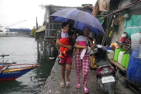 Residents carry their children as they evacuate to safer grounds to prepare for the coming of Typhoon Noru at the seaside slum district of Tondo in Manila, Philippines on Sept. 25, 2022. (Photo | AP)