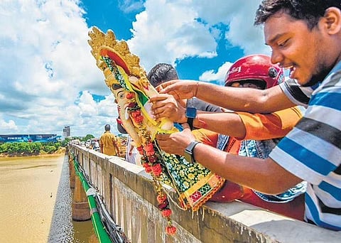 People throw a Ganesh idol into Kuakhai river in violation of BMC directive, in Bhubaneswar on Friday | Express