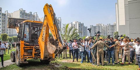 In this file photo, police personnel guard as a Noida Authority buldozer arrives for the demolition of illegal construction at the Grand Omaxe society, in Noida, on August 8, 2022. (Photo | PTI)