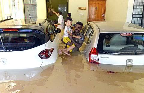 Bengaluru is reeling under severe waterlogging due to incessant heavy rains which continued to affect traffic in several areas of the city today. However, parts of the ciy that were battered by torrential rains for the last couple of days appeared to be slowly returning to normalcy with floodwaters receding in some areas. (IN PIC: An official poses with a child rescued from a flooded house/ ANI)
