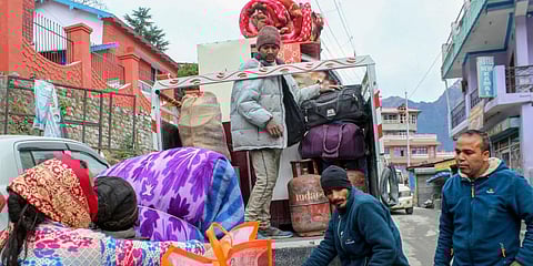 People affected by the gradual 'sinking' of the houses shift their belongings to a safer place, in Joshimath. (Photo | PTI)
