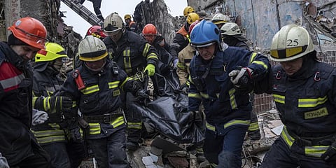 Rescue workers carry the body of a man who was killed in a Russian missile strike on an apartment building in the southeastern city of Dnipro.(Photo | AP)