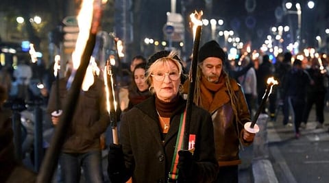 Protesters take part in a torch-lit march called by the CGT workers' union to protest the French government's pensions reform plan. (Photo | AFP)