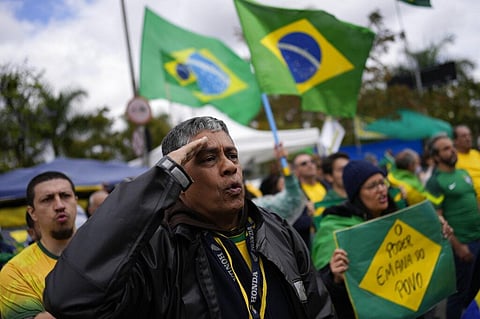 A  Bolsonaro supporter salutes while singing the nation's anthem outside a military base during a protest against his reelection defeat in Sao Paulo, Nov. 3, 2022. (File Photo | AP)