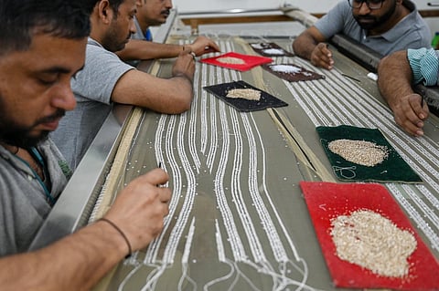 Embroiderers of Shanagar, a luxury Mumbai-based hand-embroidery atelier, work on a design for French couturier Julien Fournié, at a production facility in Mumbai. (Photo | AFP)