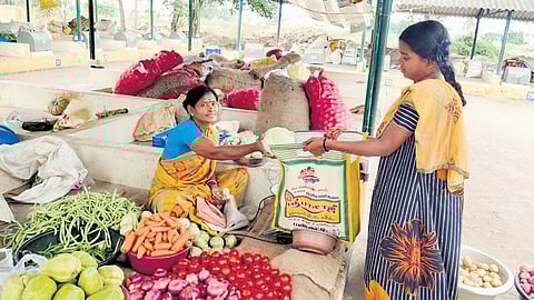 A girl buys vegetables from the shop in Uzhavar Santhai in Perambalur | express