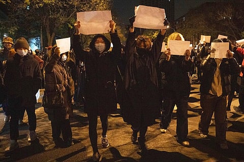 Protesters hold up blank papers and chant slogans as they march in protest in Beijing, Nov. 27, 2022.  (File Photo | AP)