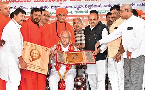 Former CM BS Yediyurappa is conferred with the Madivala Machideva Award in Chitradurga on Thursday in the presence of Chief Minister Basavaraj Bommai | Express