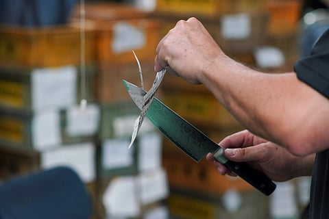 This picture taken on September 2, 2022 shows a worker testing the sharpness of a knife in the manufacturing process at a factory of Sumikama Cutlery in Seki, Gifu prefecture. (File Photo | AFP)