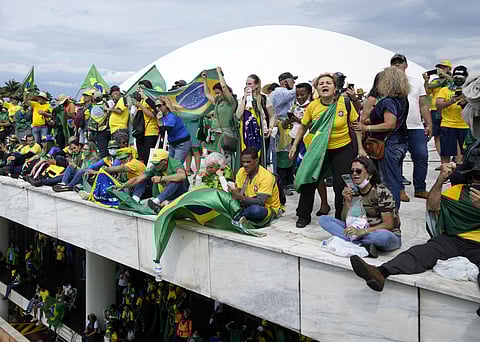 Protesters, supporters of Brazil's former President Jair Bolsonaro, stand on the roof of the National Congress building after they stormed it. (Photo | AP)