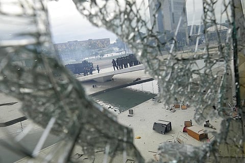 Police in riot gear are seen through a shattered window as they form up outside Planalto Palace after protesters stormed the Palace in Brasilia on Jan. 8, 2023 | AP