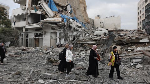 Palestinian women walk through debris amid the destruction from Israeli airstrikes in Gaza.