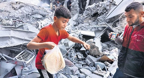 A Palestinian youth carries bread amid the rubble in the Gaza Strip  | AFP