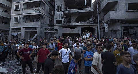 Palestinians watch others looking for injured in the rubble of a destroyed residential building following an Israeli airstrike. (Photo | AP)