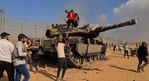 Palestinians take control of an Israeli Merkava battle tank after crossing the border fence with Israel from Khan Yunis in the southern Gaza Strip. (Photo | AFP)
