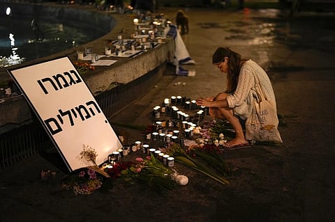 A woman lights candles in honor of victims of the Hamas attacks during a vigil at Dizengoff square in central Tel Aviv, Israel, Friday, Oct. 13, 2023.