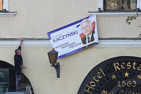 Workers hoisting campaign banner of ruling Law and Justice leader Jaroslaw Kaczynski. (Photo | AP)