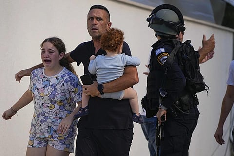 Israeli police officers evacuate a family from a site hit by a rocket fired from the Gaza Strip, Ashkelon, Oct 7, 2023. (Photo | AP)