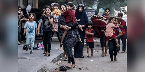 Palestinian women with their children fleeing from their homes following Israeli air strikes rush along a street in Gaza City on October 11, 2023. (Photo | AFP)